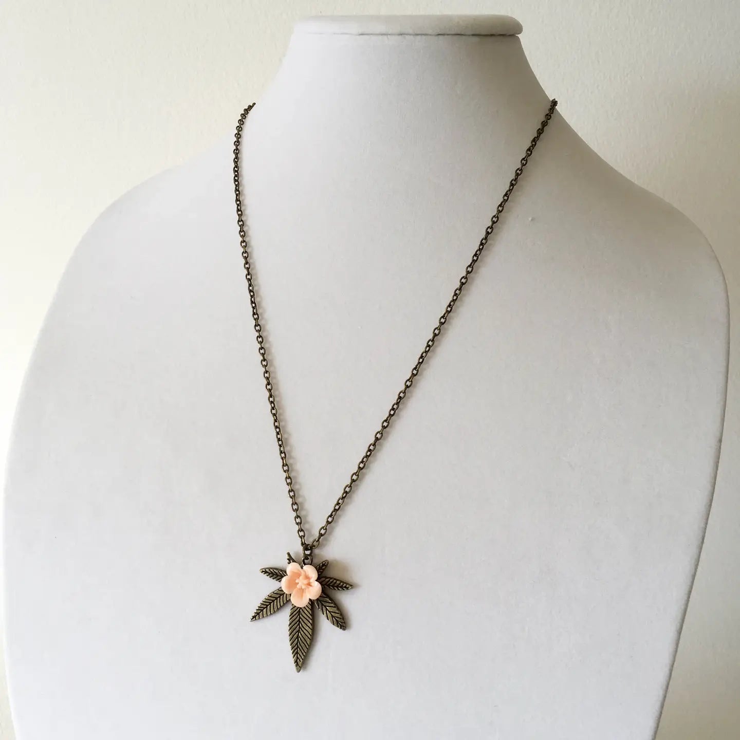 Necklace with a floral pendant on a mannequin bust against a plain background
