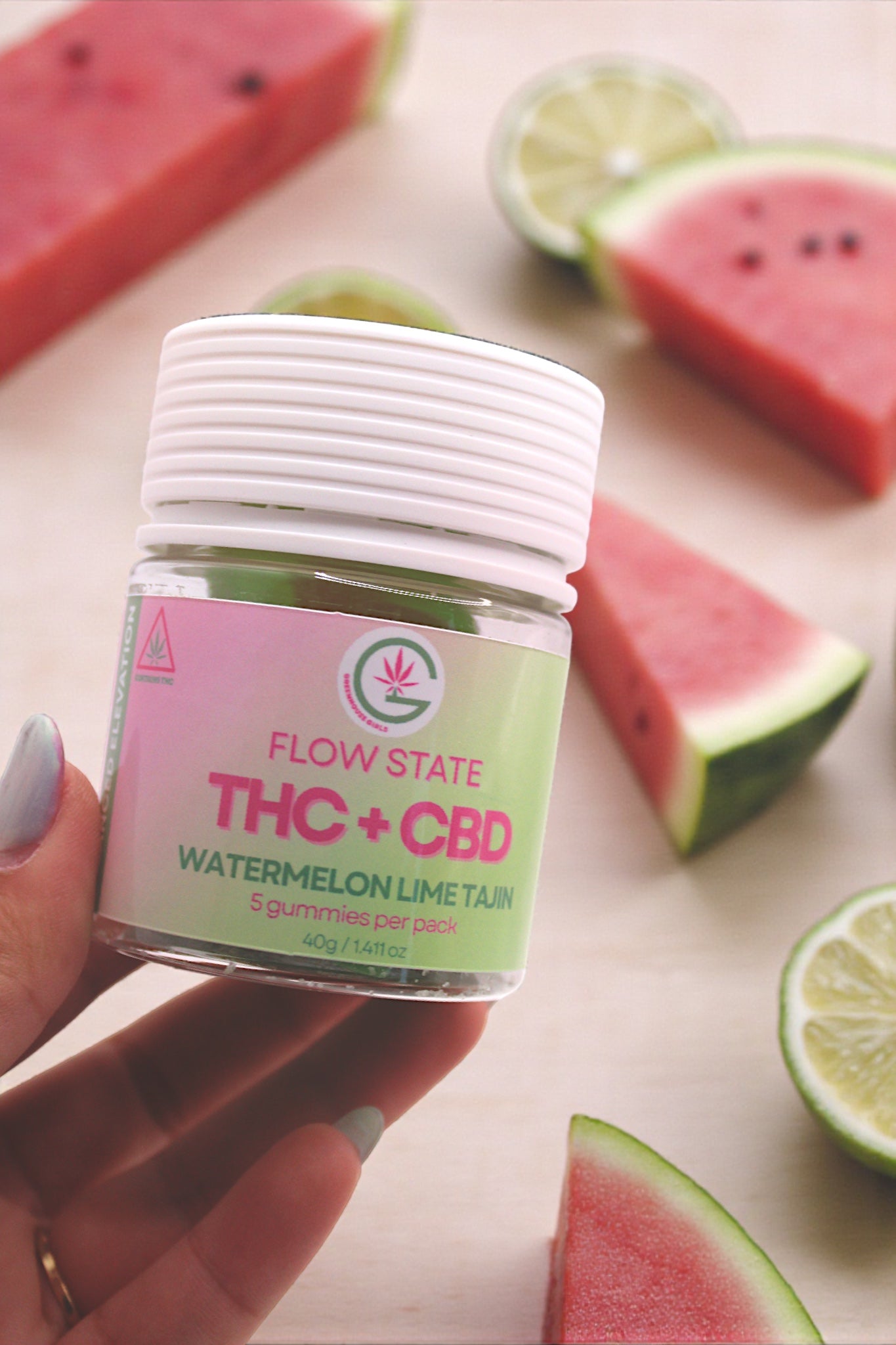 Jar of Flow State THC + CBD Watermelon Lime gummies with watermelon slices and lime halves on a light background.