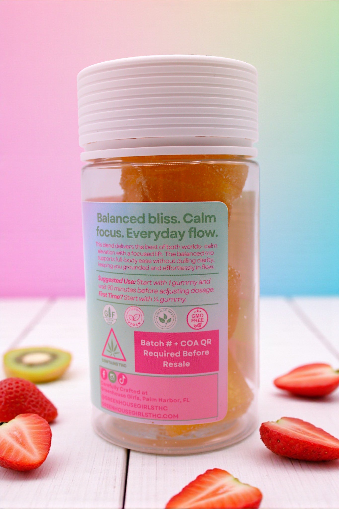 Bottle of a supplement with a colorful label on a white surface with fruits.