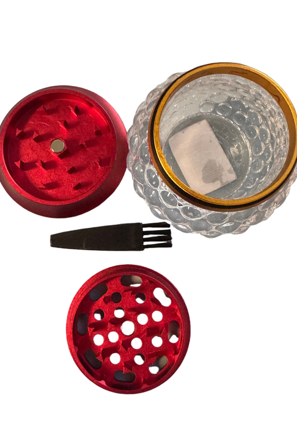 Red metal grinders and a clear glass container on a white surface