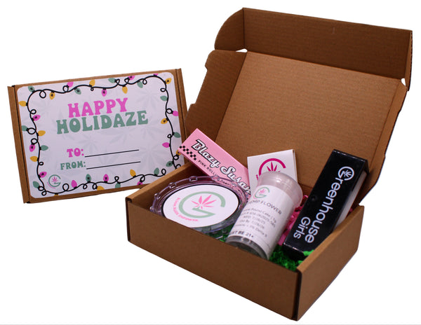 Open cardboard box with beauty products and a 'Happy Holidaze' card on a white background