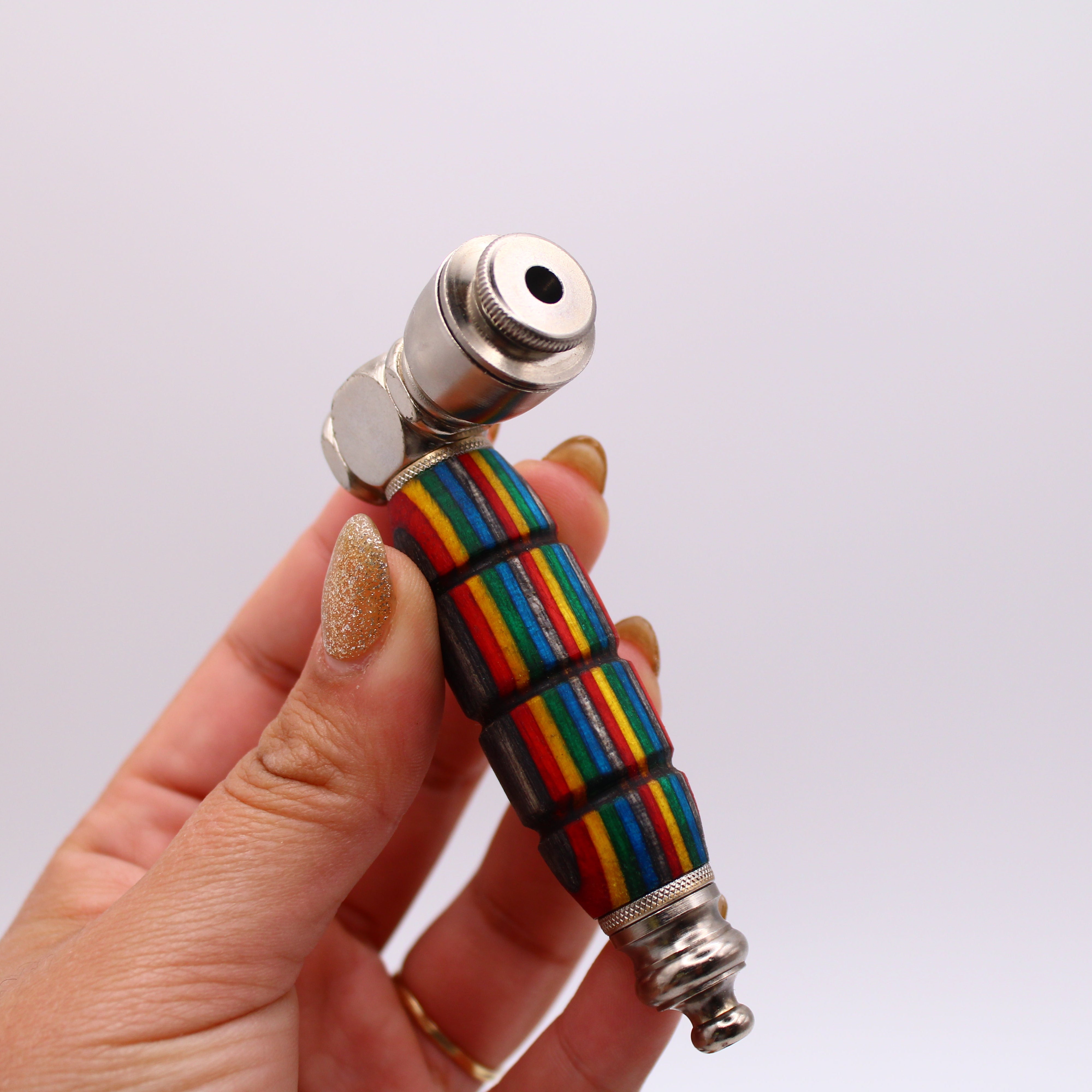 Hand holding a rainbow-patterned pipe against a white background