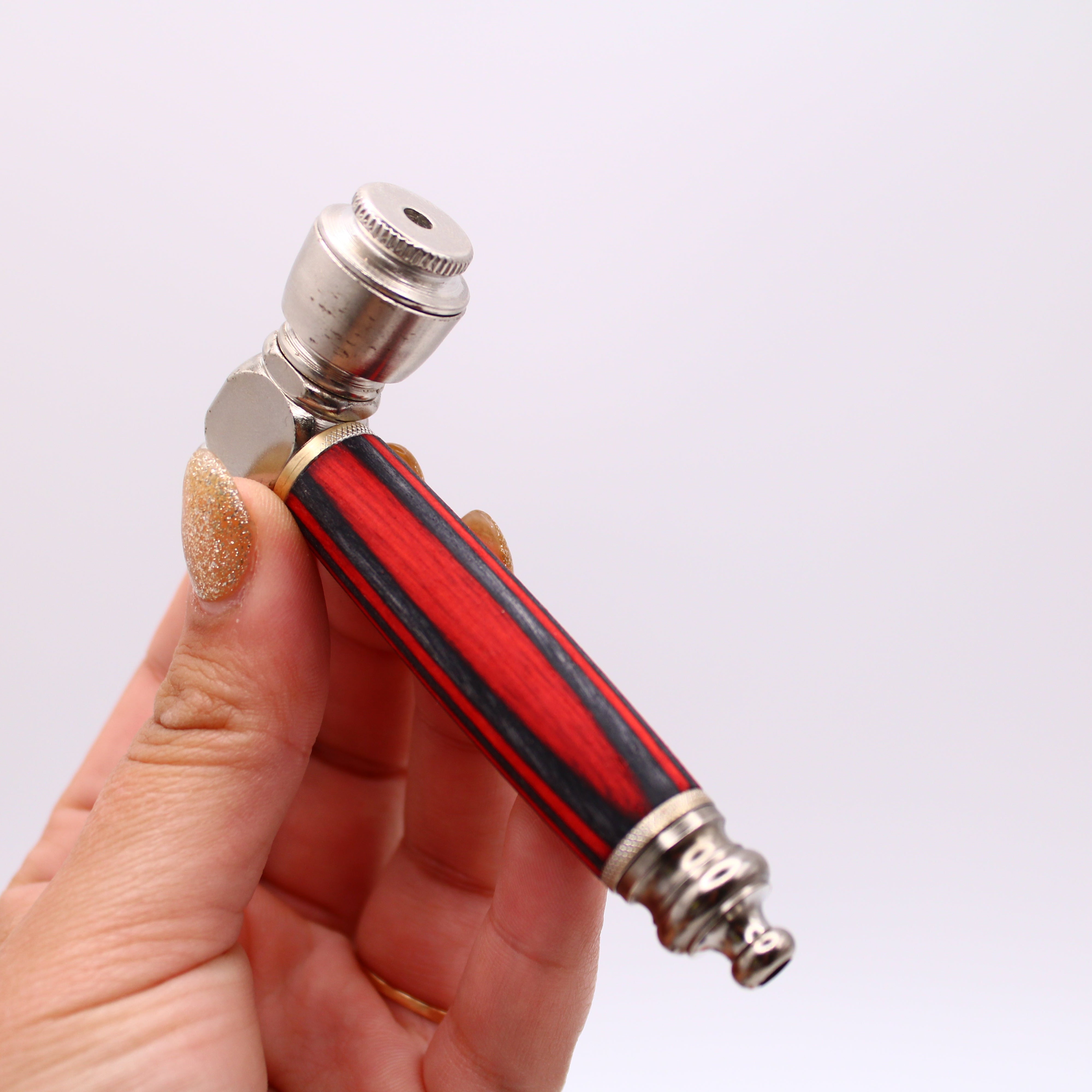 Hand holding a red and silver pipe against a white background