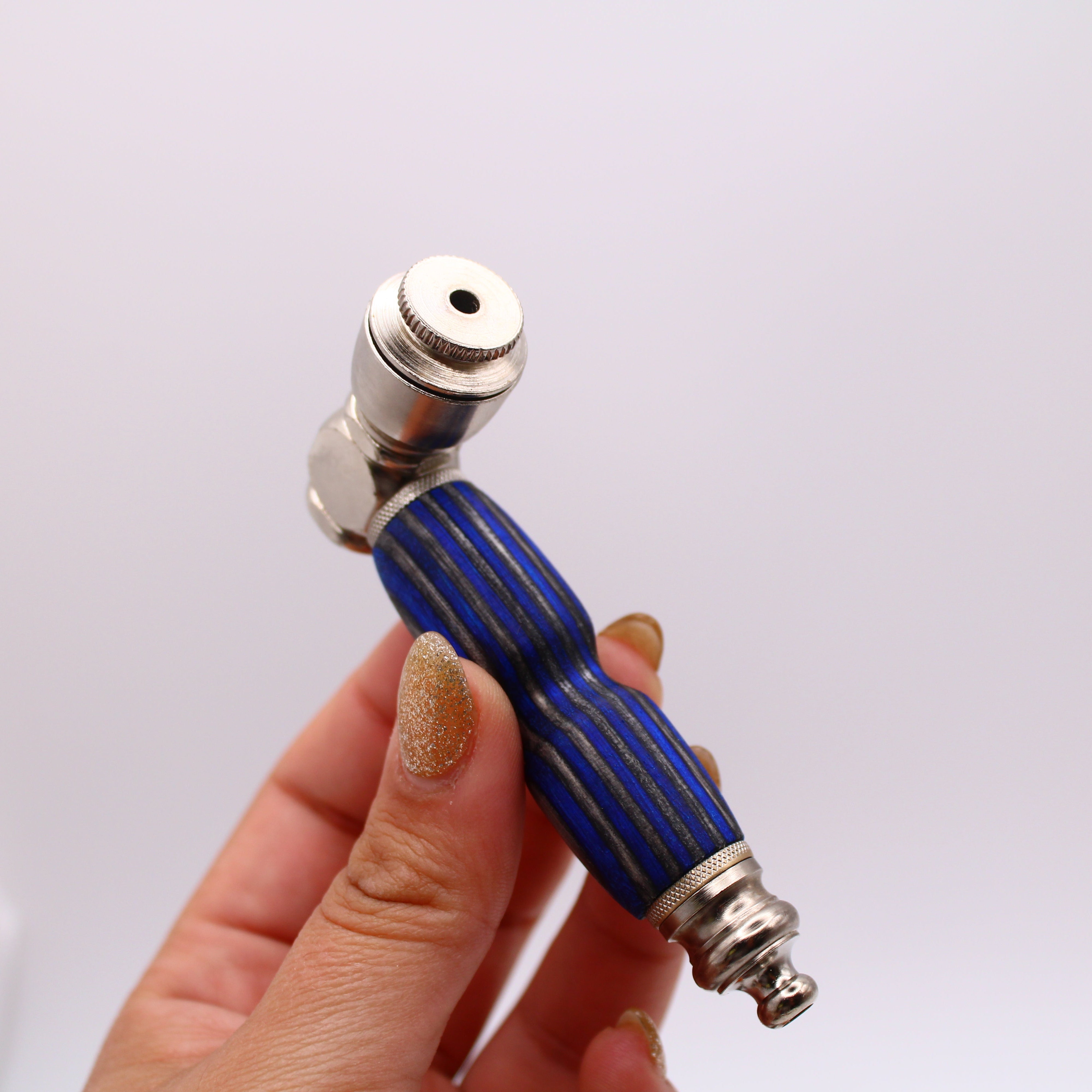 Hand holding a blue and silver pipe against a white background