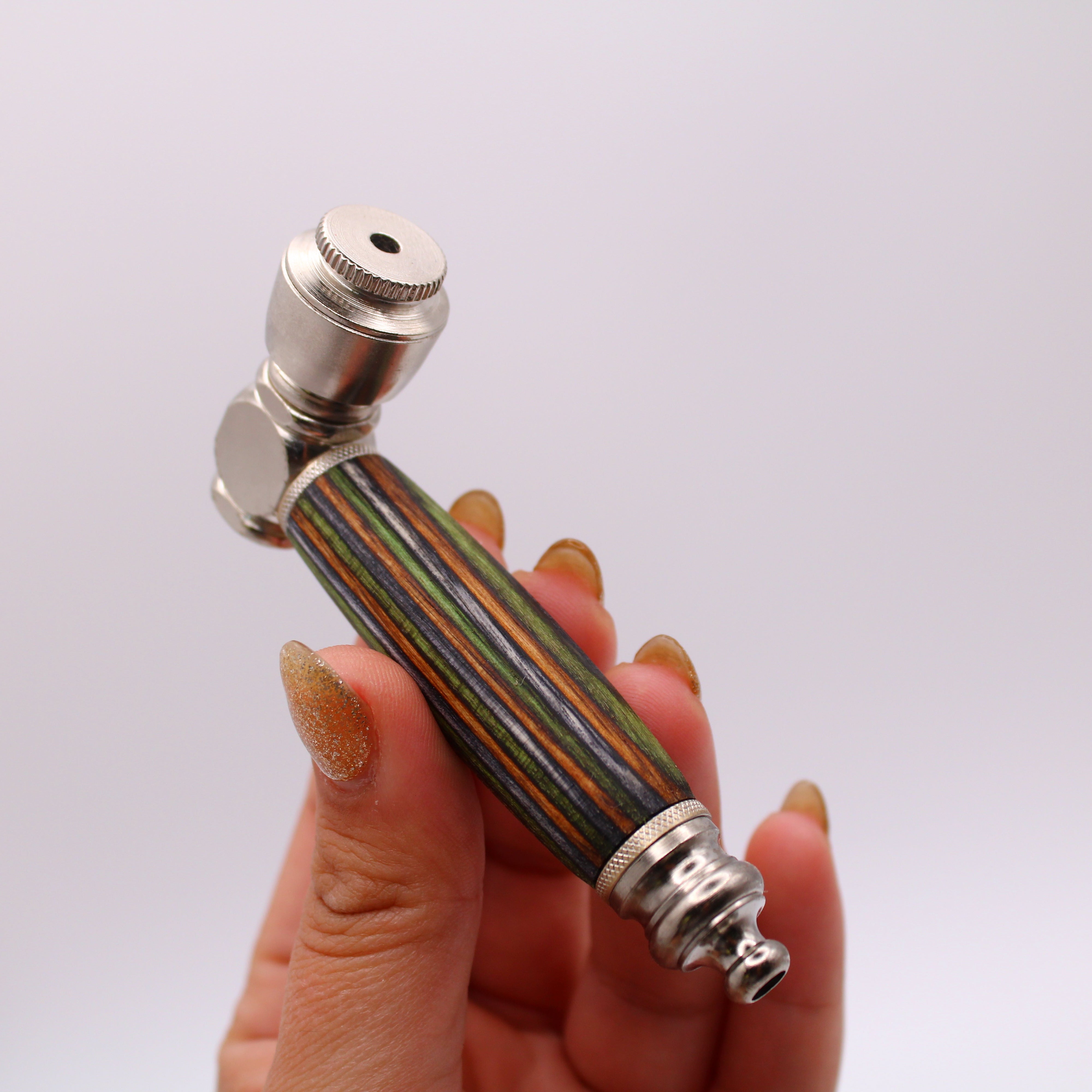 Hand holding a pipe with a striped handle and metallic top against a white background