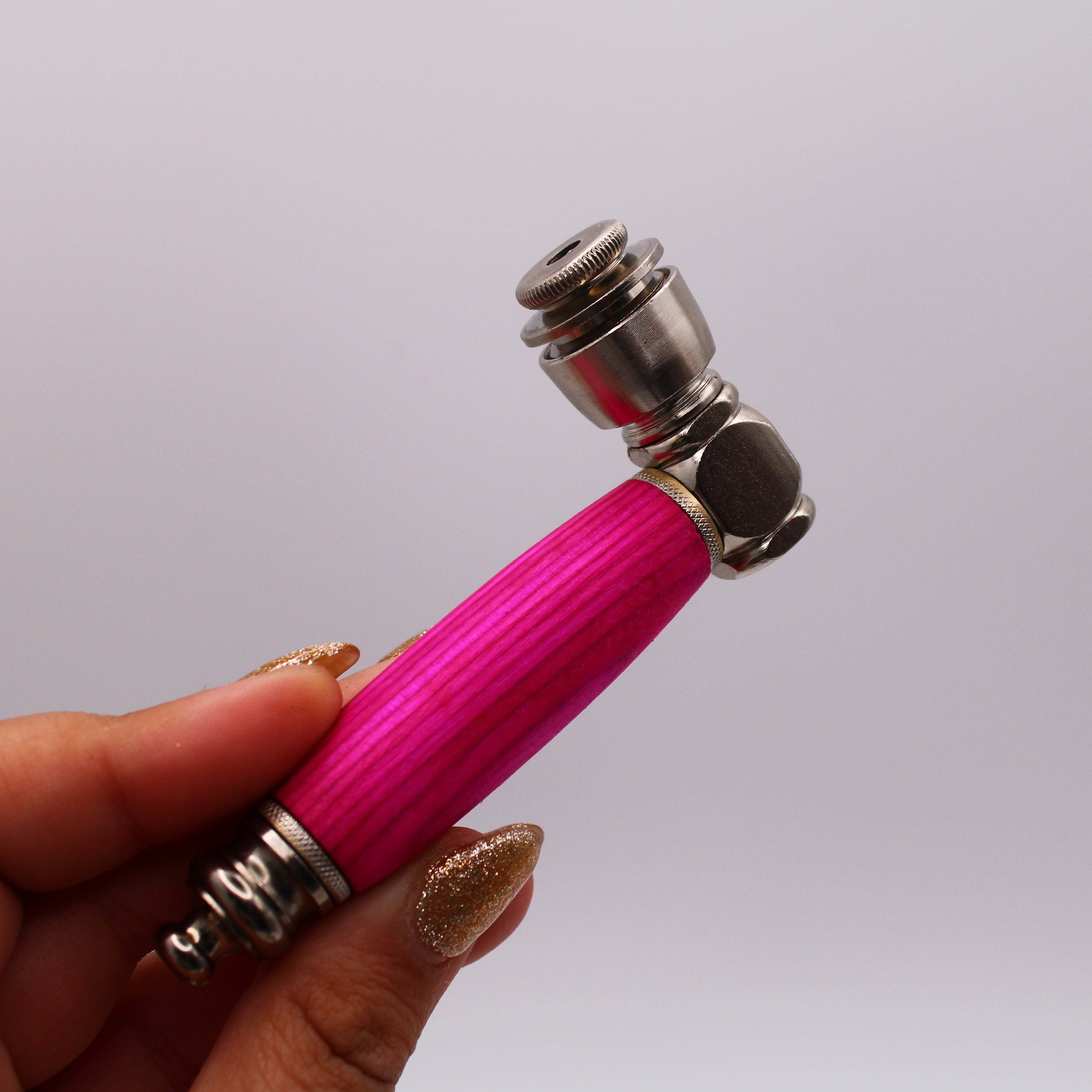 Pink-handled pipe held by a hand against a plain background