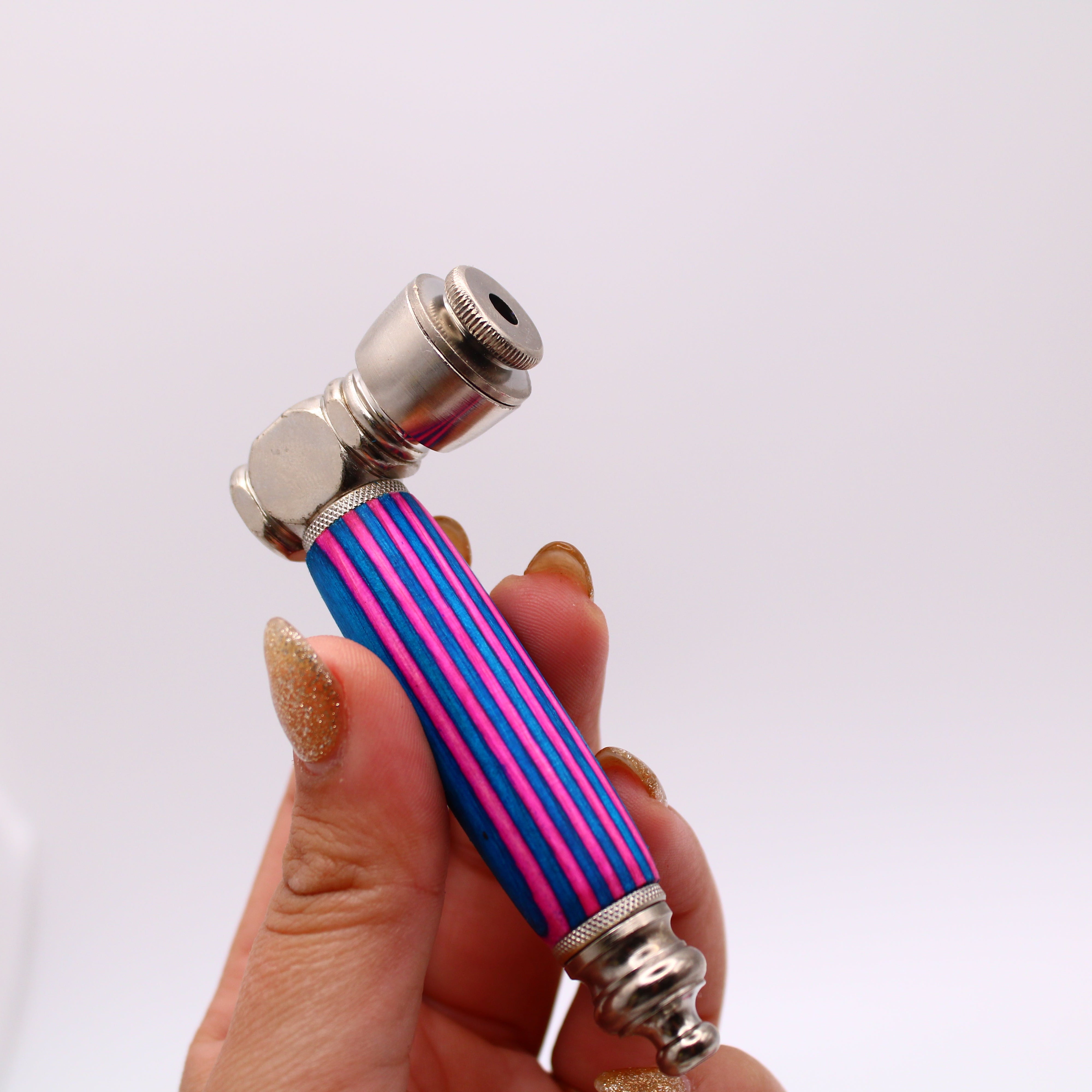Hand holding a striped pink and blue pipe against a white background