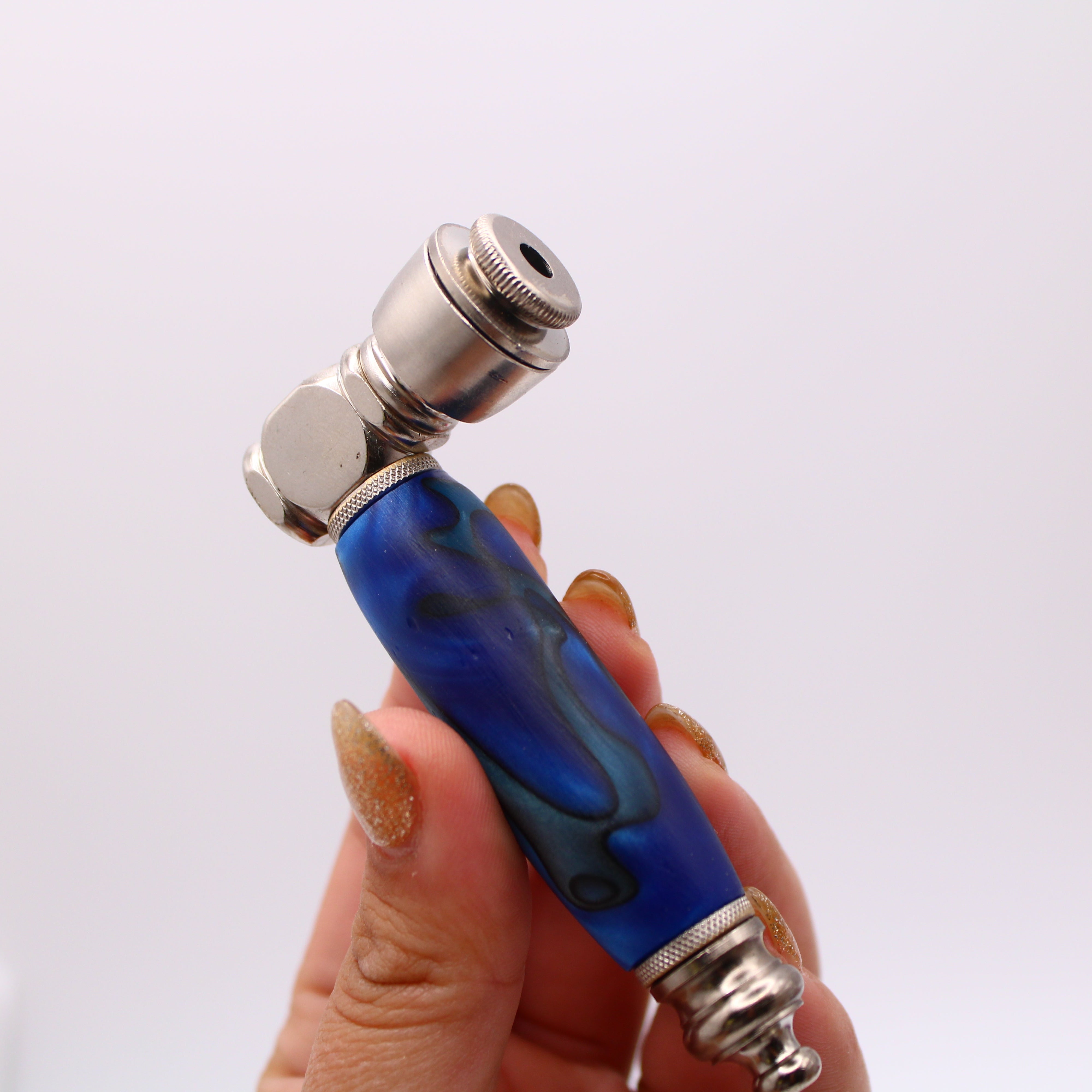 Blue and silver smoking pipe held by a hand against a white background