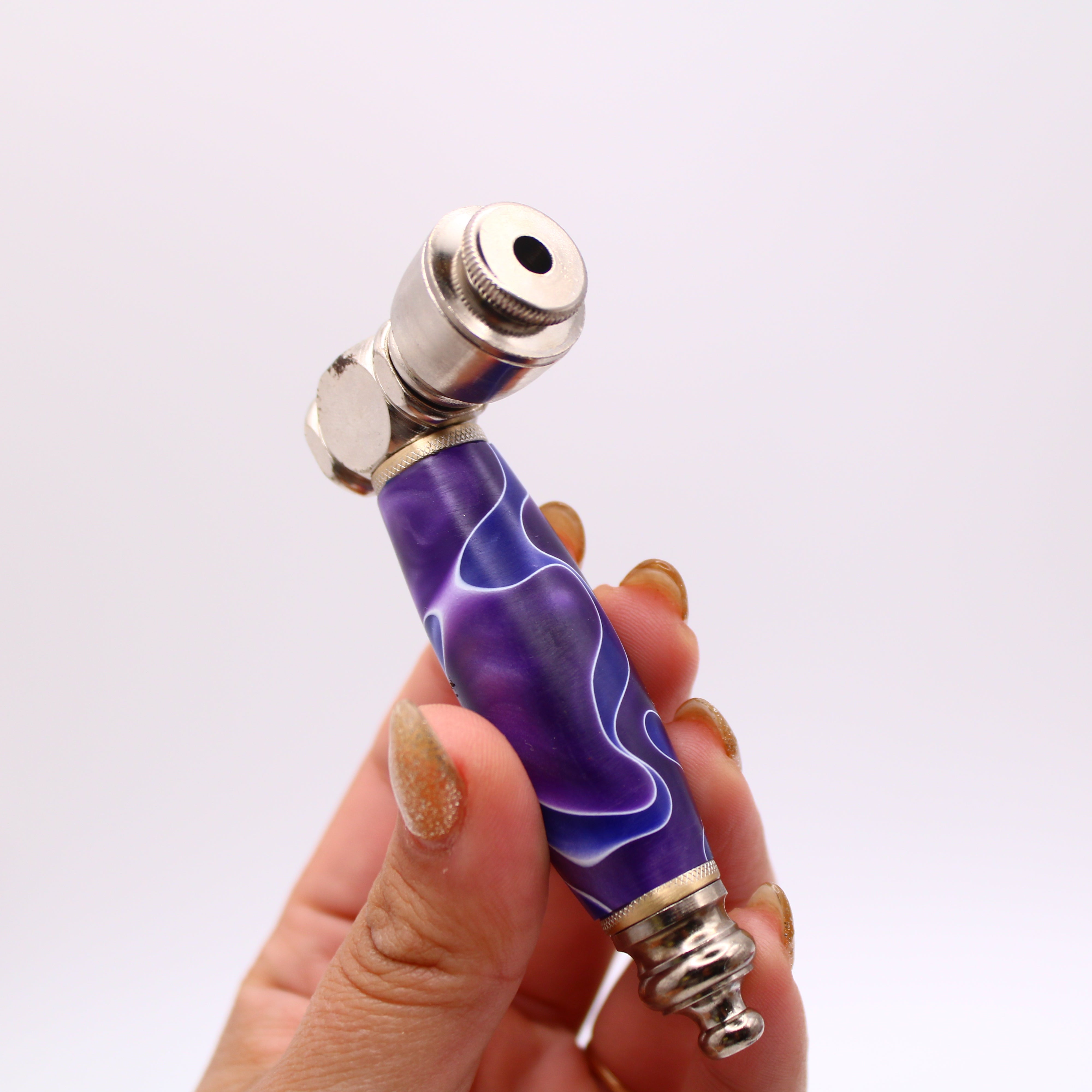 Purple and silver pen-like object held in a hand against a white background