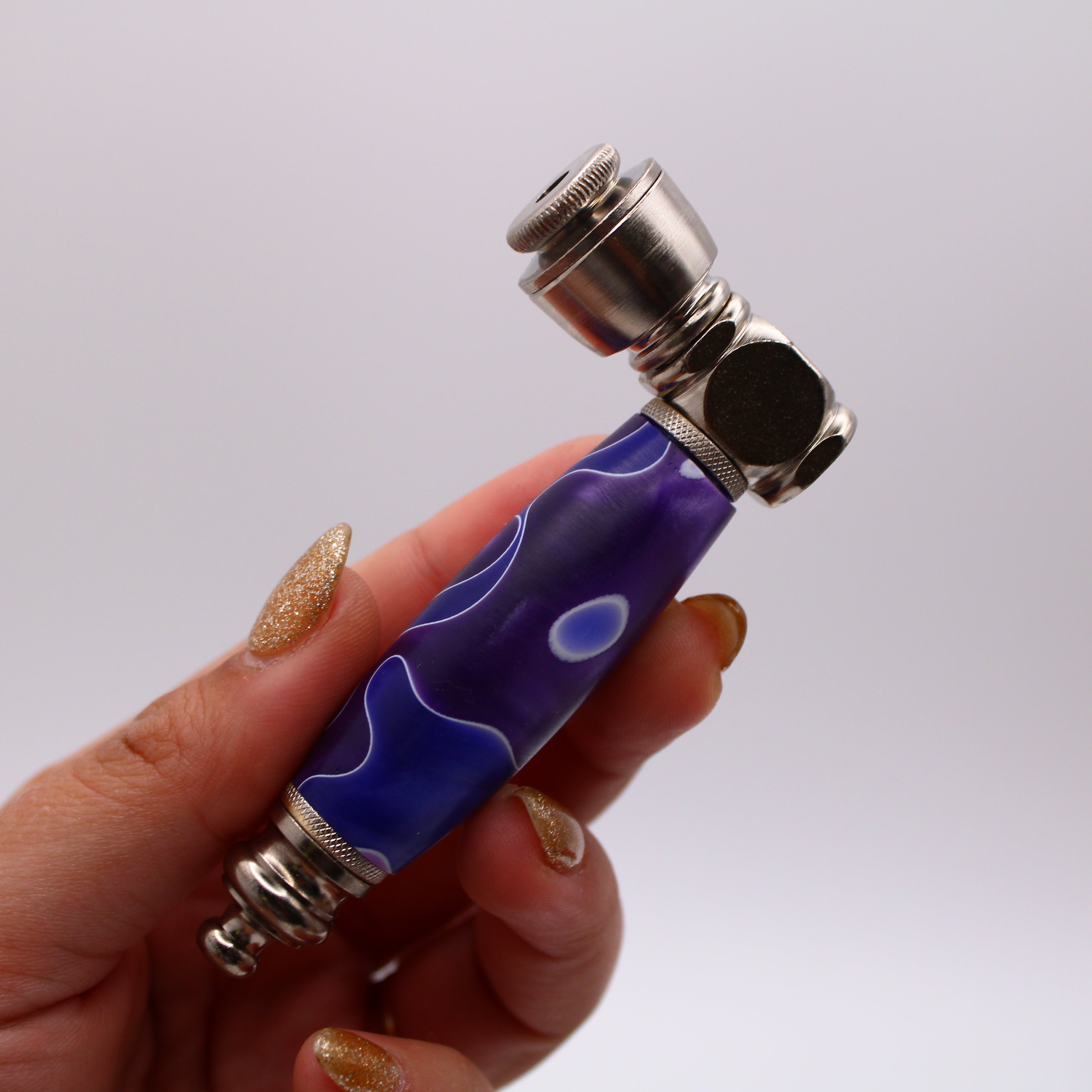 Hand holding a blue and silver pipe against a white background