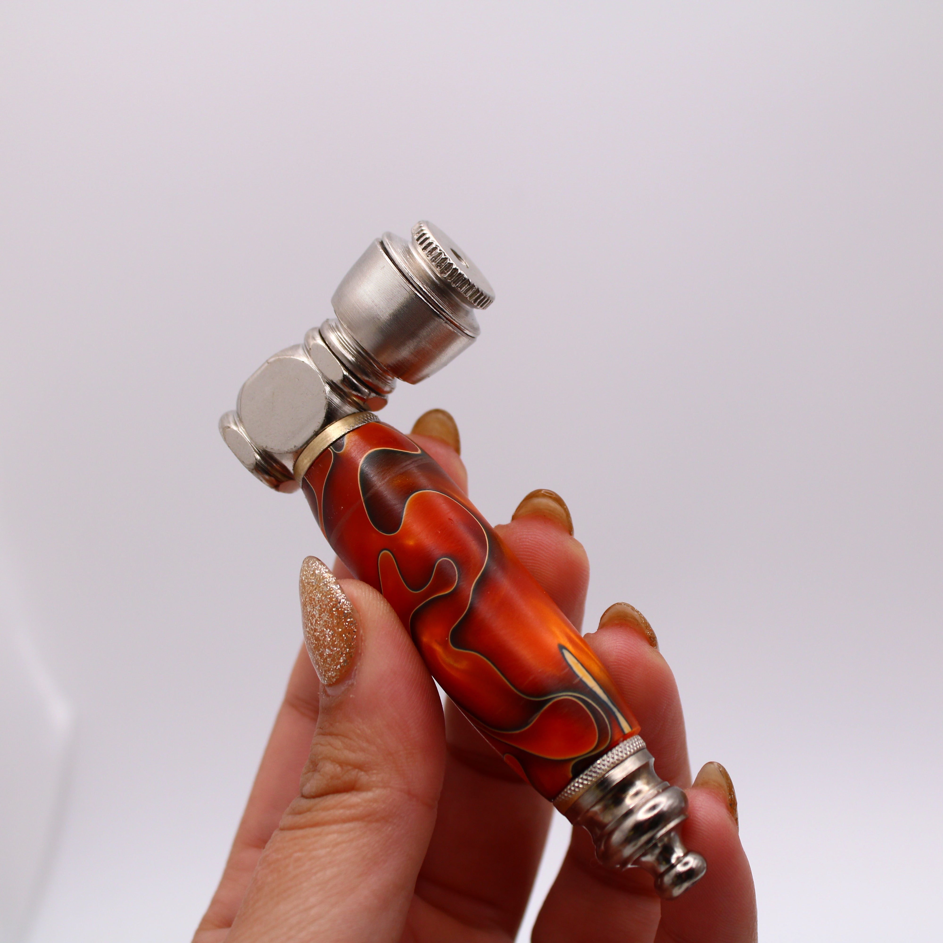 Hand holding a decorative pipe with flame design on a white background