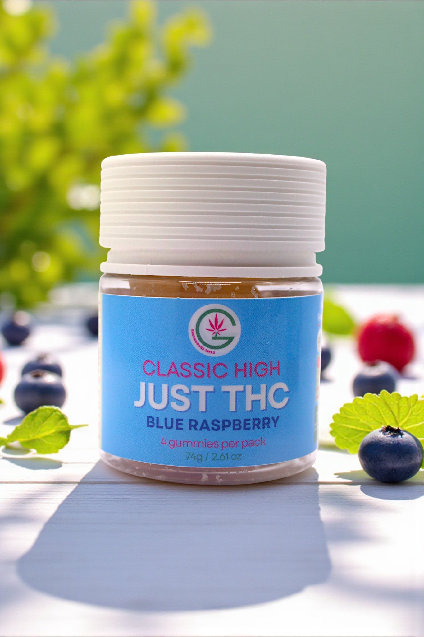 Jar of 'Just THC' blue raspberry flavor on a light surface with greenery in the background