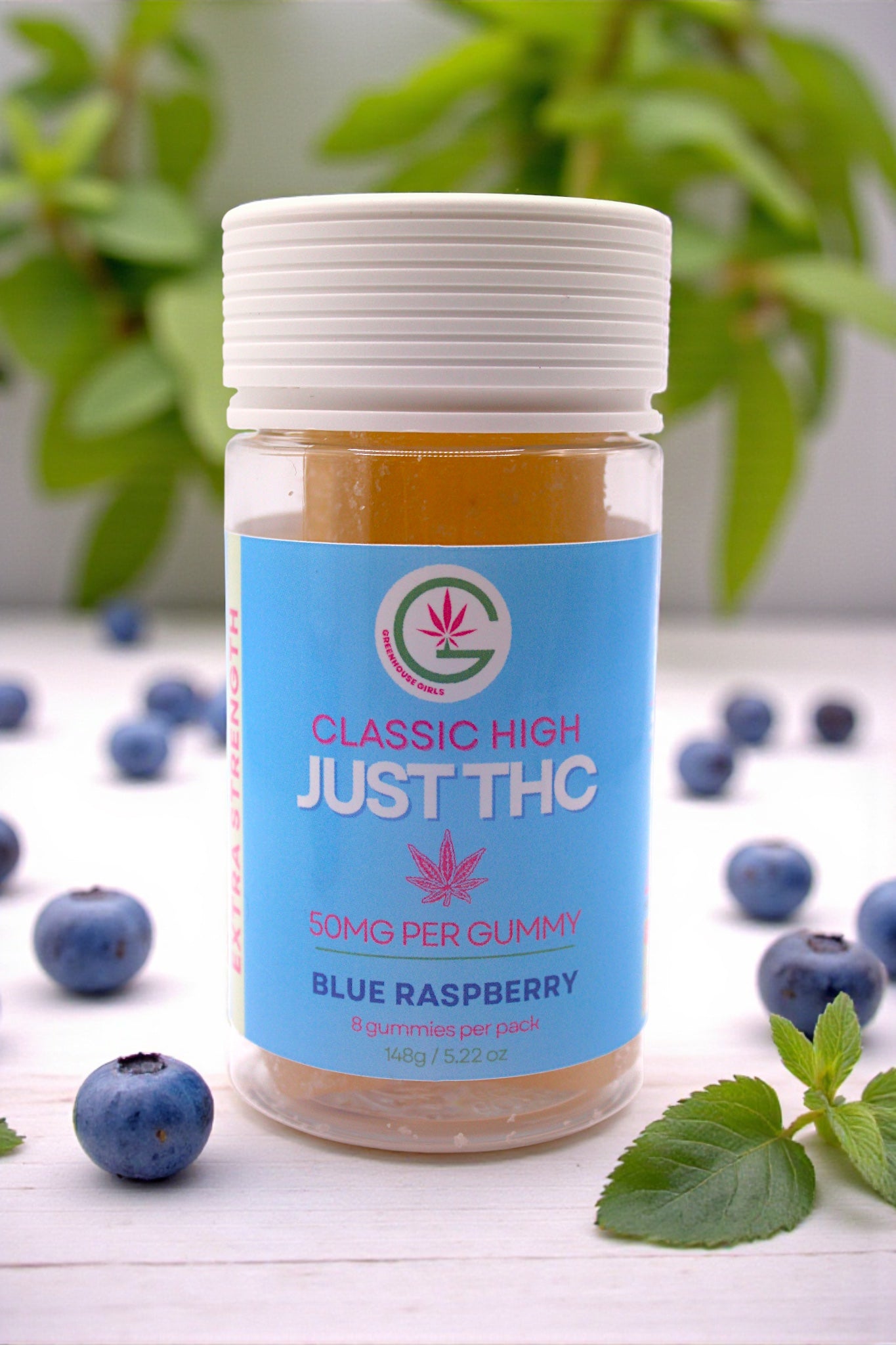 Jar of 'Just THC' blue raspberry gummies with blueberries and leaves on a white surface