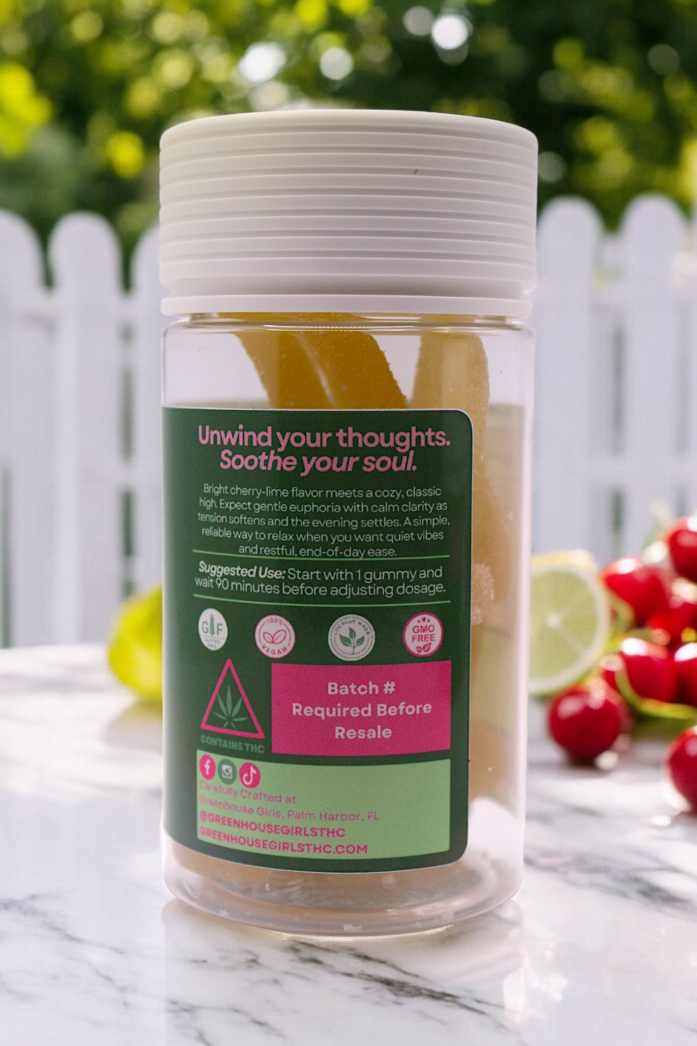 Jar of a natural product with a green label on a marble surface with fruits in the background.