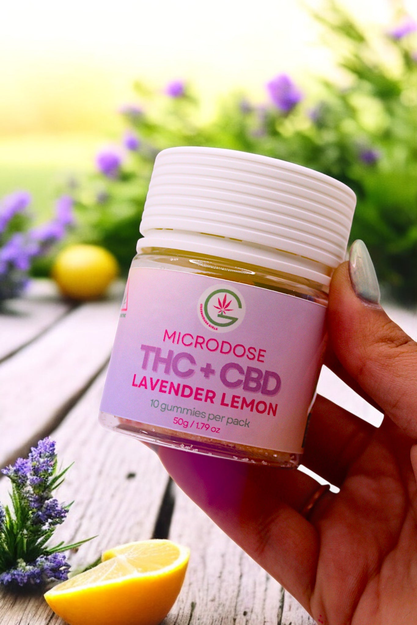 Hand holding a container of 'Microdose THC + CBD Lavender Lemon' gummies with a blurred natural background.