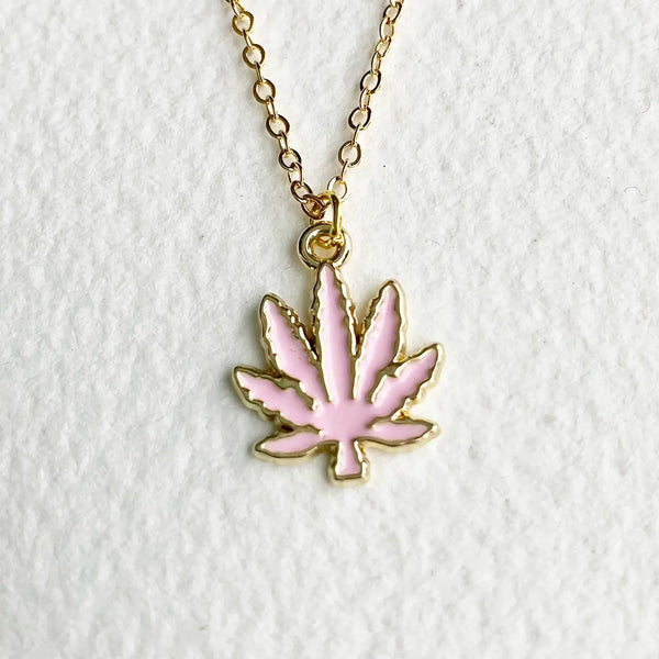 Pink cannabis leaf pendant on a gold chain against a white background