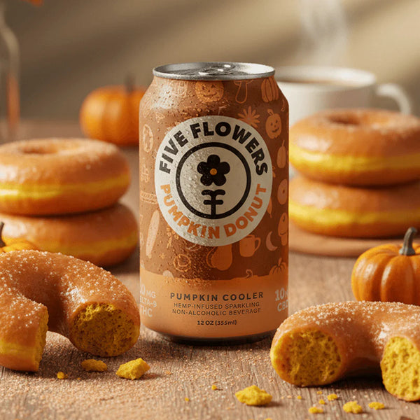 Can of Five Flowers Pumpkin Donut beer surrounded by pumpkin donuts and pumpkins on a wooden surface.