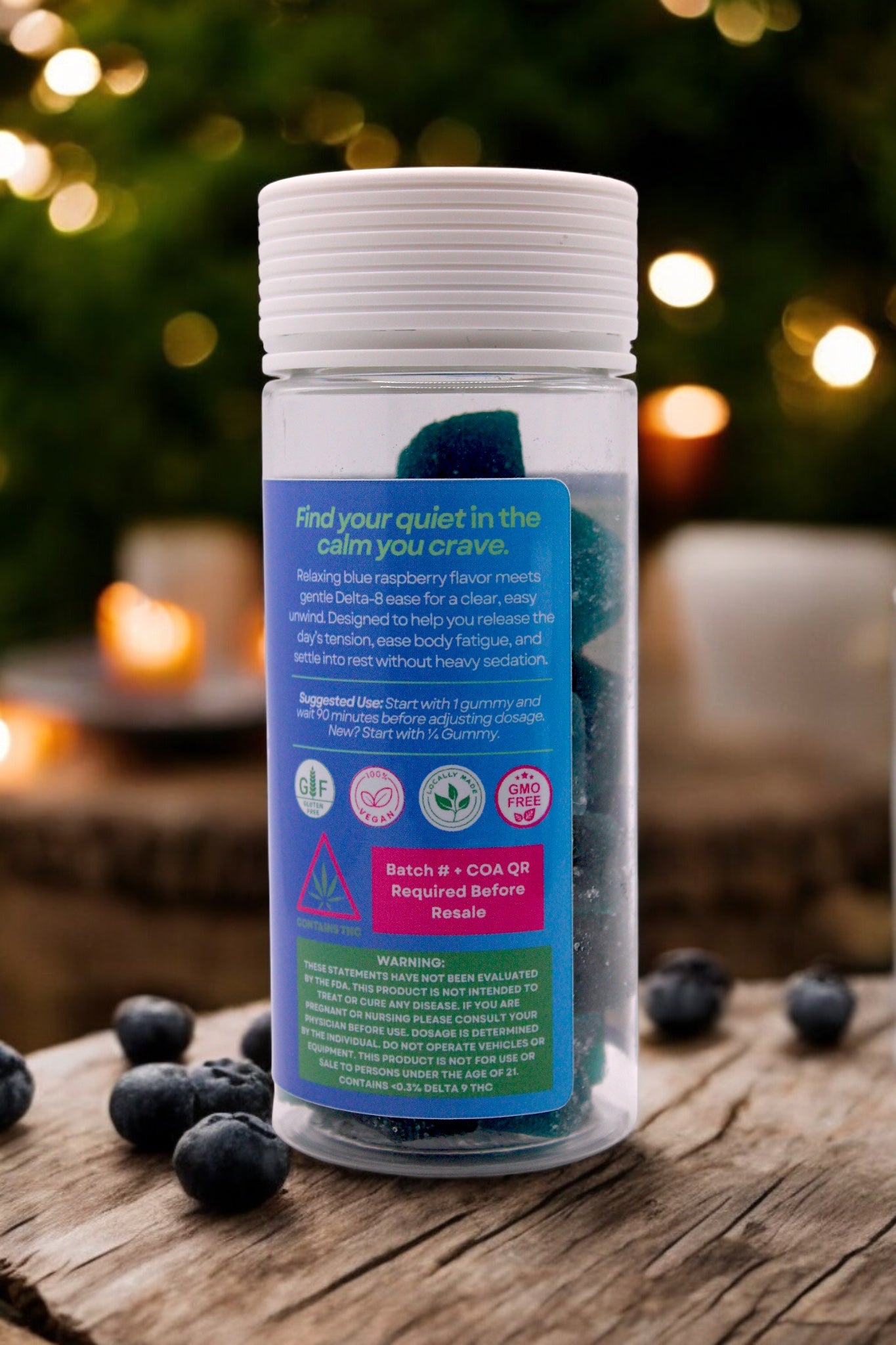 Bottle of blueberry-flavored supplement on a wooden surface with blurred lights in the background