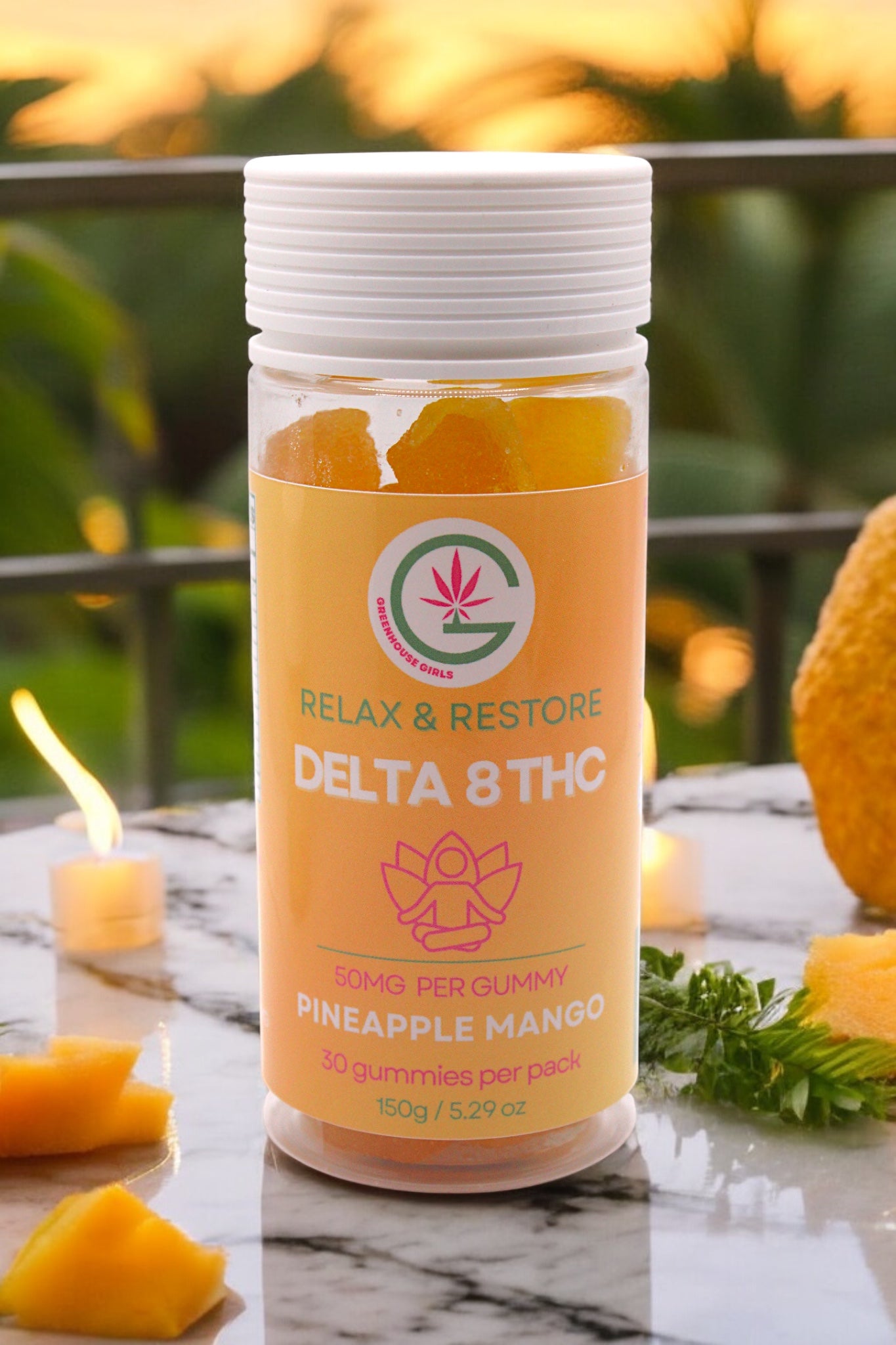 Container of Delta 8 THC gummies with pineapple mango flavor on a marble surface with candles and greenery.