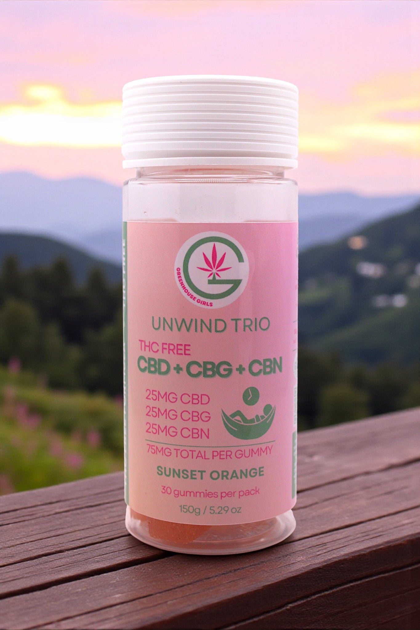 Pink supplement bottle labeled 'Unwind Trio' with a mountainous background