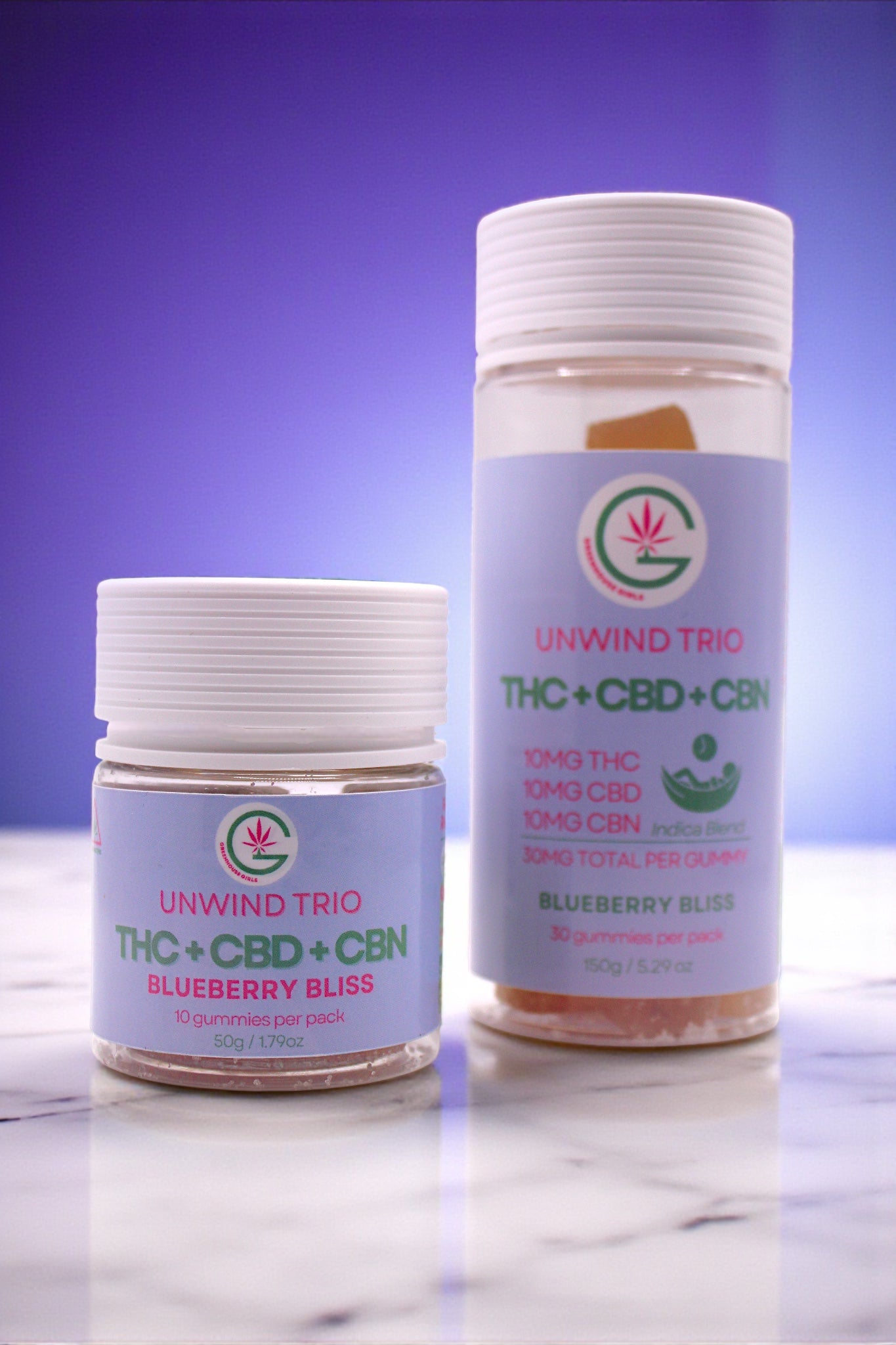 Two containers of 'Unwind Trio' THC + CBD + CBN Blueberry Bliss on a marble surface with a purple gradient background.