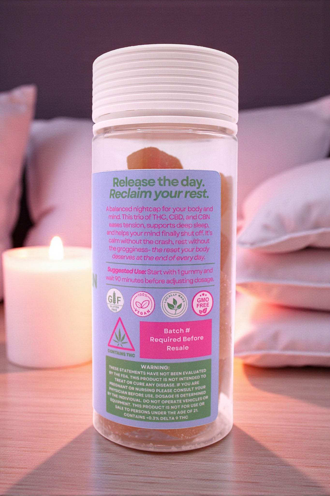Bottle of a product with a label on a surface with pillows and a candle in the background