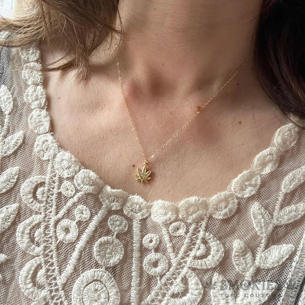 Necklace with a small pendant worn by a person against a lace garment background